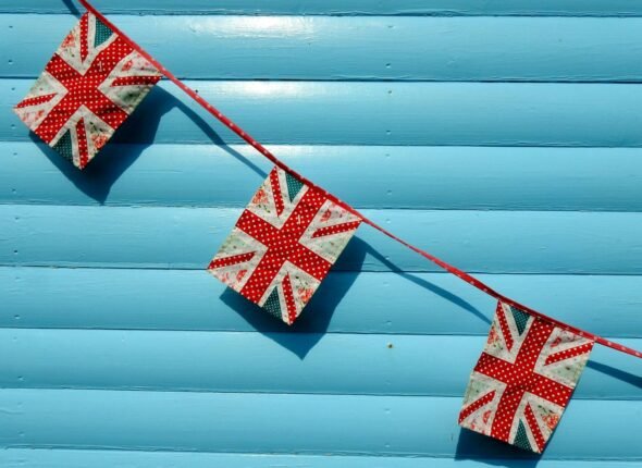 Close-up of Union Jack buntings against a vivid blue wall, perfect for UK-themed events.