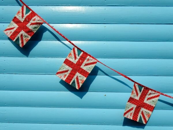 Close-up of Union Jack buntings against a vivid blue wall, perfect for UK-themed events.