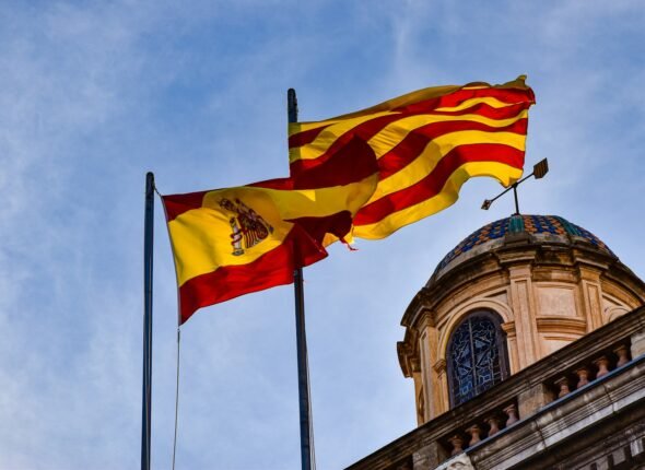 two flags flying next to each other in front of a building