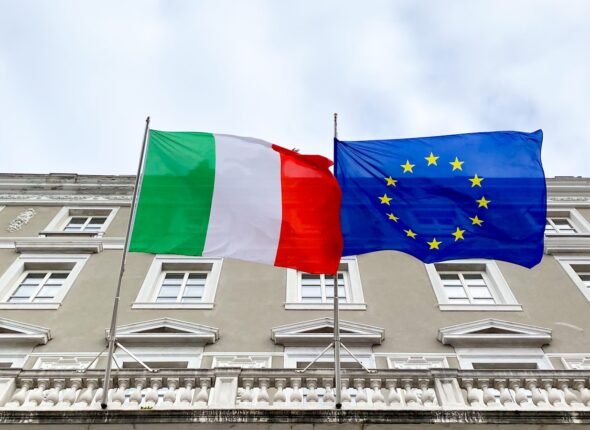 two flags are flying in front of a building