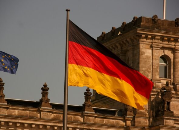 two flags flying next to each other in front of a building