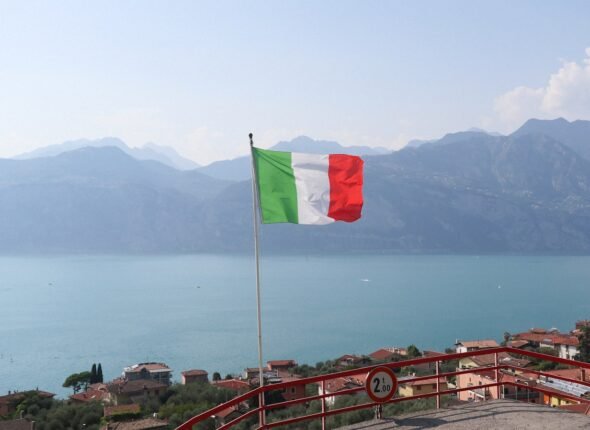 a flag flying on top of a hill next to a body of water